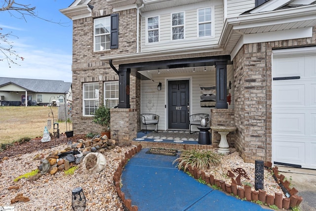 entrance to property with brick siding, covered porch, and an attached garage