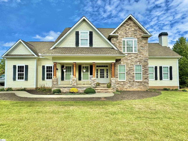 craftsman house with a front lawn, stone siding, covered porch, a shingled roof, and a chimney