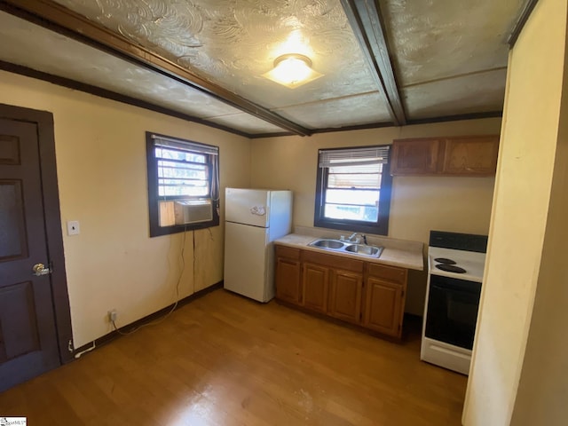 kitchen with freestanding refrigerator, a sink, range with electric cooktop, light countertops, and a wealth of natural light