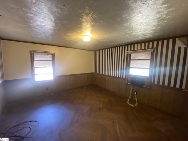 spare room featuring a wainscoted wall, a textured ceiling, and wood walls