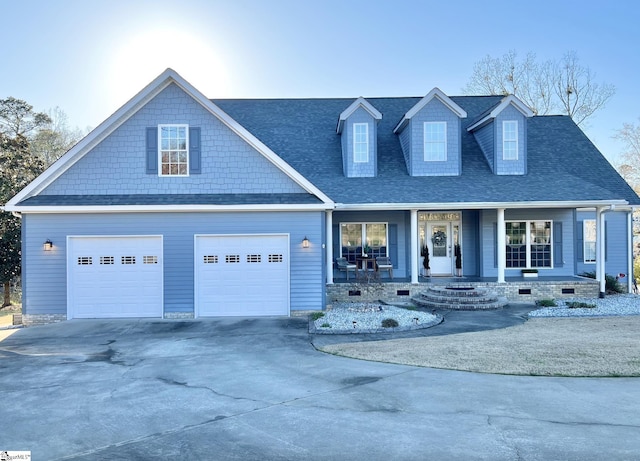 view of front of property featuring concrete driveway, a garage, covered porch, and roof with shingles