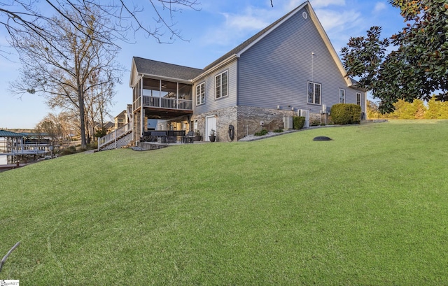 rear view of property featuring stairway, a lawn, and a sunroom