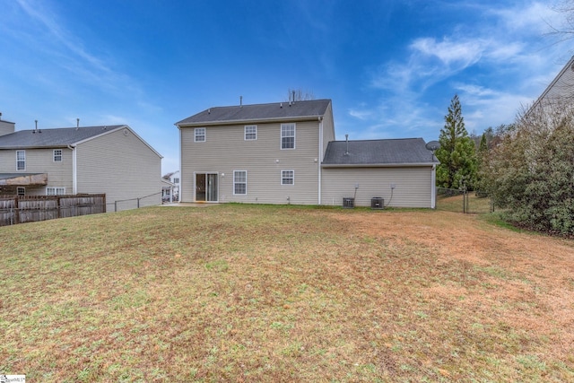 rear view of property featuring central AC unit, a lawn, and fence