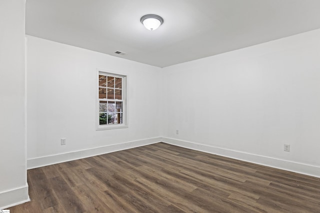 spare room with visible vents, baseboards, and dark wood-style floors