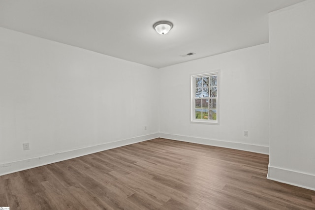 unfurnished room featuring visible vents, baseboards, and wood finished floors