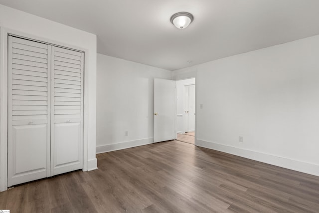 unfurnished bedroom featuring a closet, baseboards, and wood finished floors