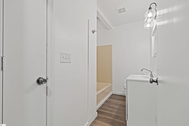 full bath with visible vents, toilet, a tub to relax in, wood finished floors, and vanity