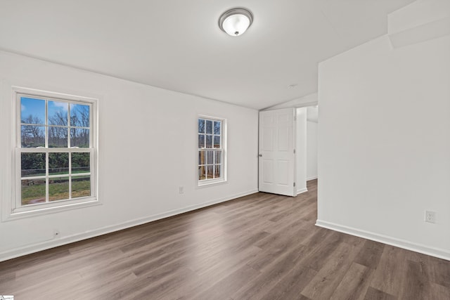 empty room with baseboards, lofted ceiling, and wood finished floors