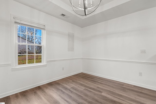 spare room featuring visible vents, baseboards, a tray ceiling, and wood finished floors