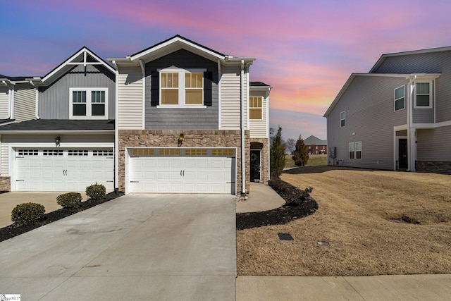 view of property with stone siding, board and batten siding, concrete driveway, and a garage