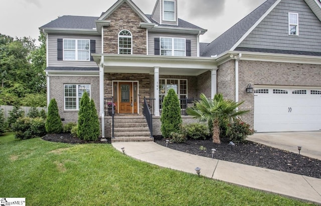 view of front of home featuring brick siding, a porch, a front yard, stone siding, and driveway