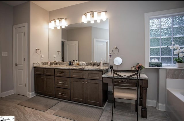 full bath with a bath, plenty of natural light, double vanity, and a sink