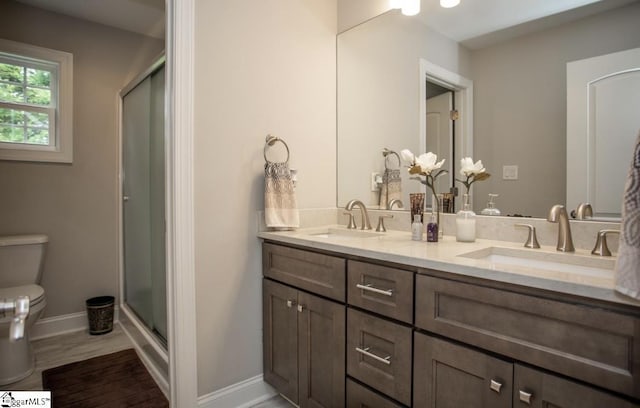 full bath featuring a stall shower, toilet, baseboards, and a sink