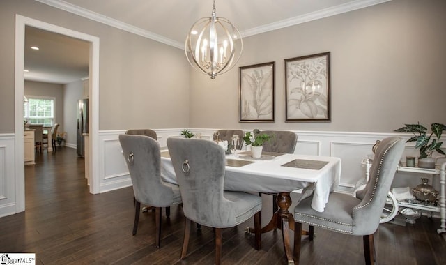 dining space featuring crown molding, dark wood-type flooring, wainscoting, a notable chandelier, and a decorative wall