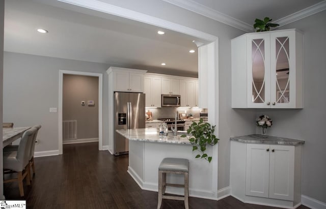 kitchen with visible vents, light stone counters, appliances with stainless steel finishes, white cabinets, and dark wood-style flooring