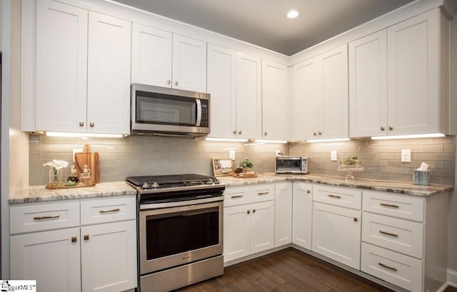 kitchen featuring dark wood-type flooring, appliances with stainless steel finishes, and white cabinetry