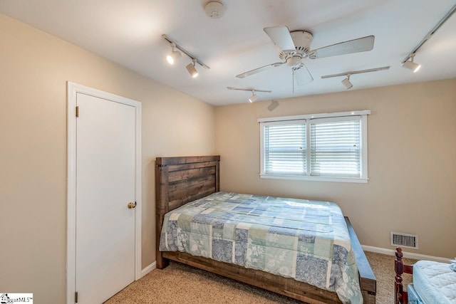 bedroom featuring a ceiling fan, baseboards, visible vents, track lighting, and light colored carpet