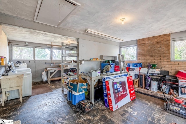 kitchen with brick wall, washer / clothes dryer, and a sink