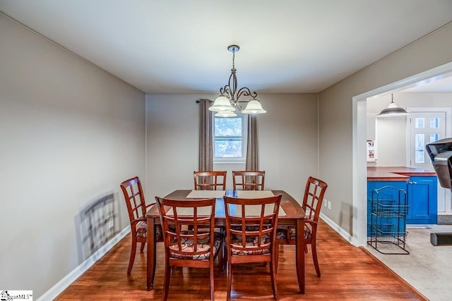 dining room featuring a notable chandelier, wood finished floors, and baseboards