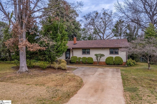 ranch-style home featuring a shingled roof, a front yard, and a chimney