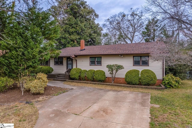 ranch-style home featuring a shingled roof, a front yard, and a chimney