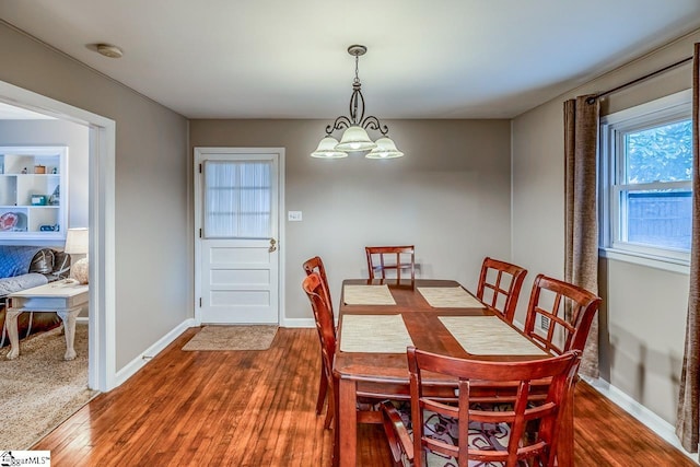 dining space with a notable chandelier, wood finished floors, and baseboards