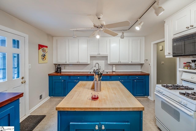 kitchen featuring white gas stove, butcher block counters, and blue cabinets