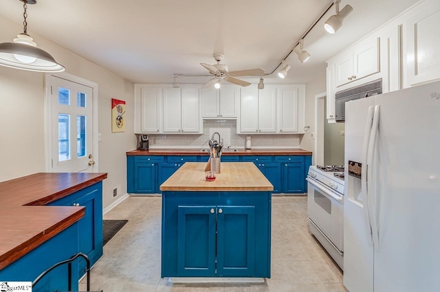 kitchen featuring white appliances, blue cabinetry, white cabinets, and butcher block counters