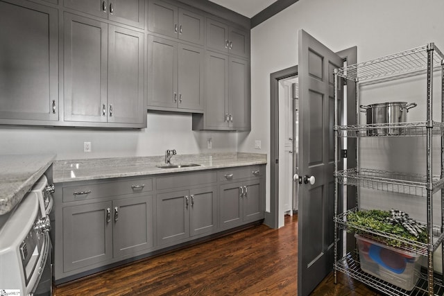 kitchen featuring a sink, light stone counters, dark wood finished floors, and gray cabinetry