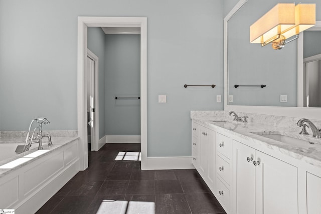 full bathroom featuring double vanity, a bathing tub, baseboards, and a sink