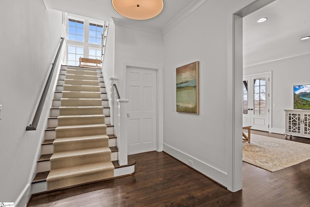 stairs with baseboards, wood finished floors, and crown molding