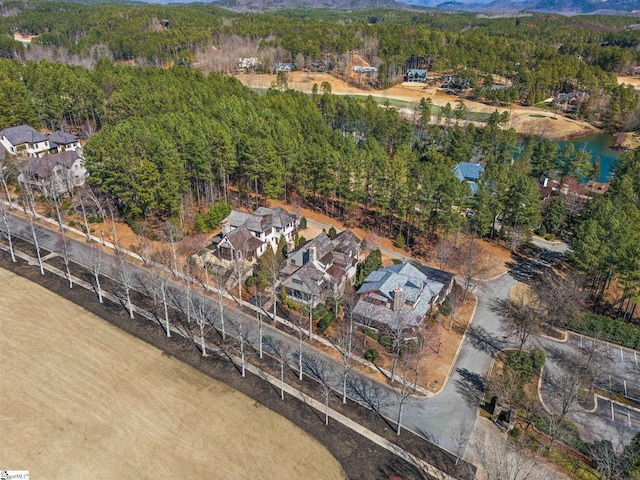 birds eye view of property featuring a water view and a wooded view