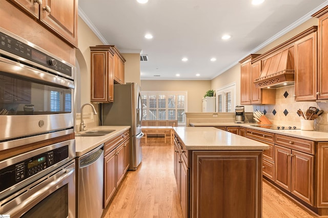 kitchen featuring a sink, light wood-type flooring, appliances with stainless steel finishes, and ornamental molding