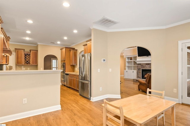 kitchen with arched walkways, visible vents, brown cabinets, and stainless steel appliances