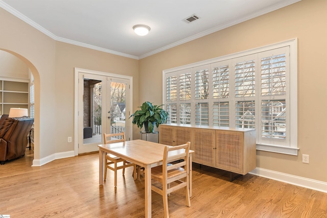 dining room with arched walkways, visible vents, light wood finished floors, and baseboards