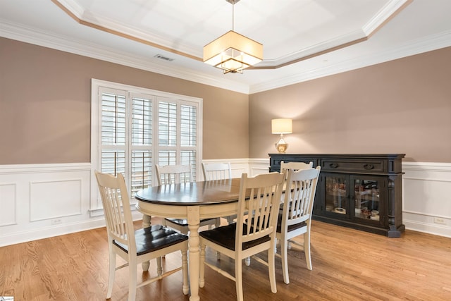 dining room featuring visible vents, a wainscoted wall, light wood-style floors, an inviting chandelier, and a raised ceiling