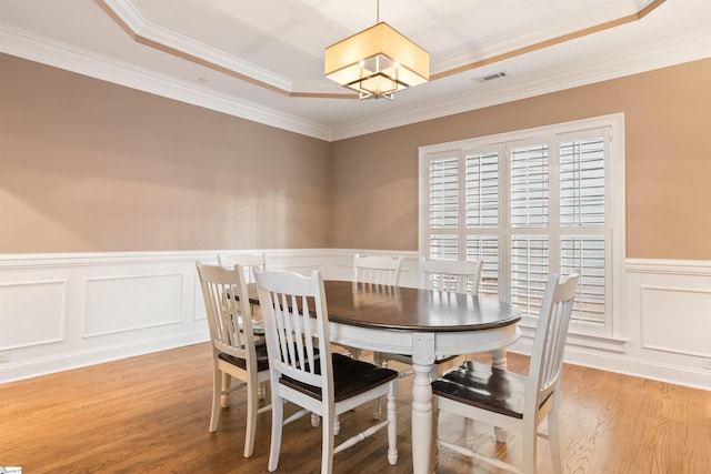 dining room featuring visible vents, an inviting chandelier, light wood-style flooring, ornamental molding, and wainscoting