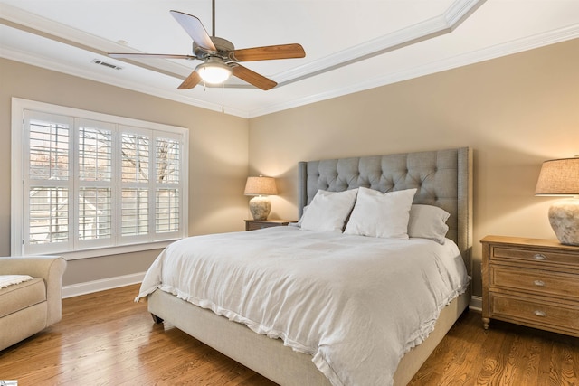 bedroom with visible vents, baseboards, wood finished floors, and ornamental molding