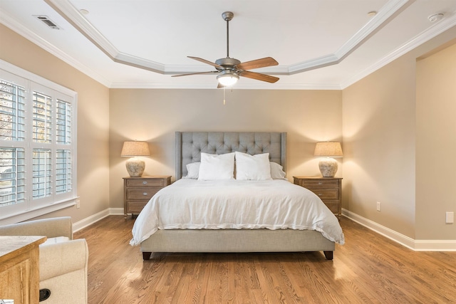 bedroom featuring a tray ceiling, wood finished floors, and crown molding