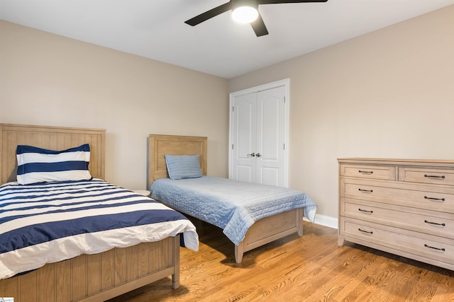 bedroom with light wood finished floors, baseboards, a ceiling fan, and a closet