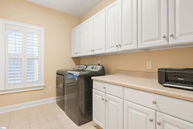 laundry area featuring washer and dryer, baseboards, cabinet space, and light tile patterned floors