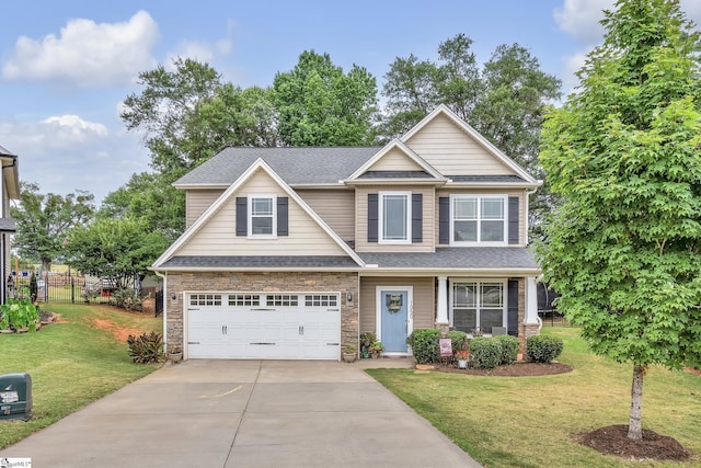 craftsman house featuring a front lawn, fence, a garage, stone siding, and driveway