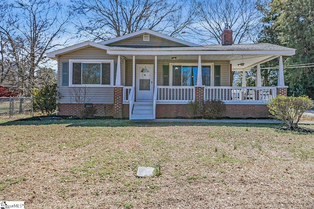 bungalow-style home with a front lawn, a porch, fence, crawl space, and a chimney