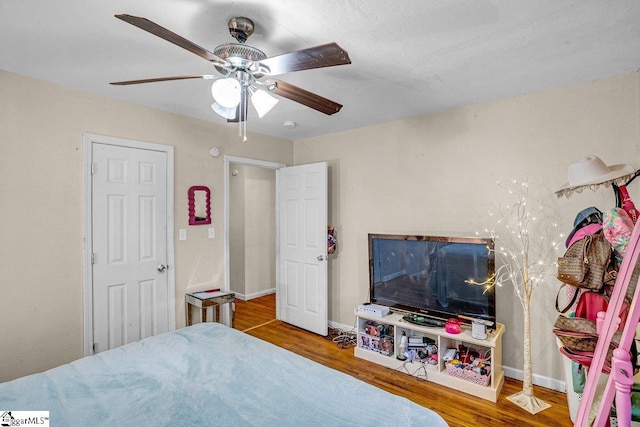 bedroom with ceiling fan, baseboards, and wood finished floors