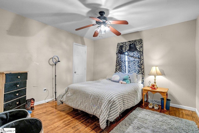 bedroom with ceiling fan, baseboards, and wood finished floors