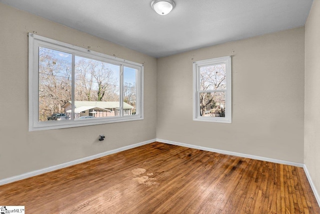 spare room featuring wood finished floors, a healthy amount of sunlight, and baseboards