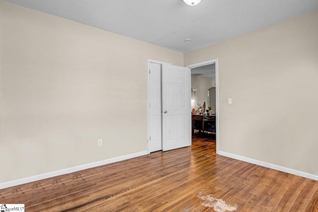 unfurnished room with baseboards and wood finished floors