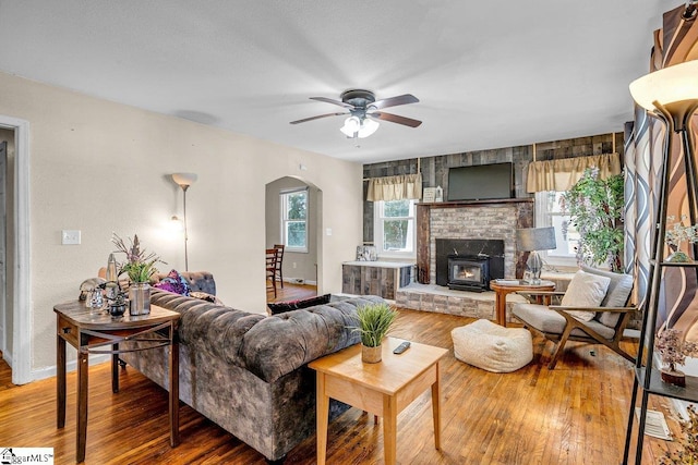 living room with baseboards, wood finished floors, arched walkways, and ceiling fan