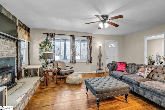 living area featuring baseboards, a ceiling fan, and wood finished floors