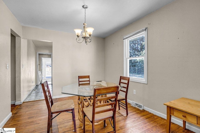 dining area with a wealth of natural light, a notable chandelier, and wood finished floors